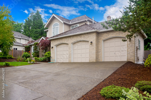 Fotografía Large beige house with three car garage and large driveway.