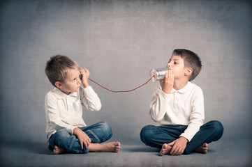 Young brothers talking with tin can telephone