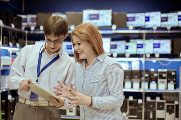 the seller-adviser shows the girl a new tablet computer