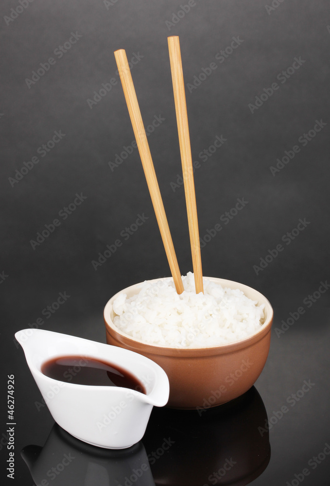 Bowl of rice and chopsticks on grey background
