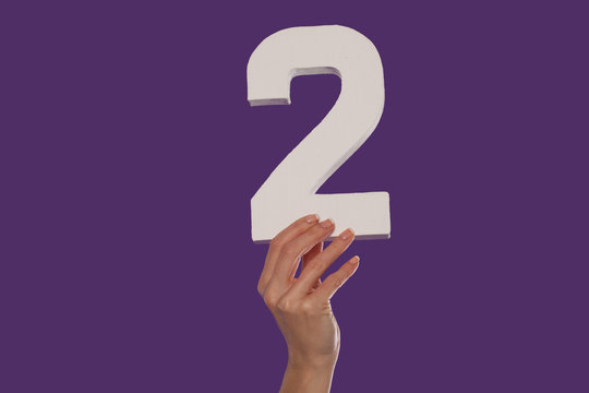 Female hand holding up the number 2 from the bottom