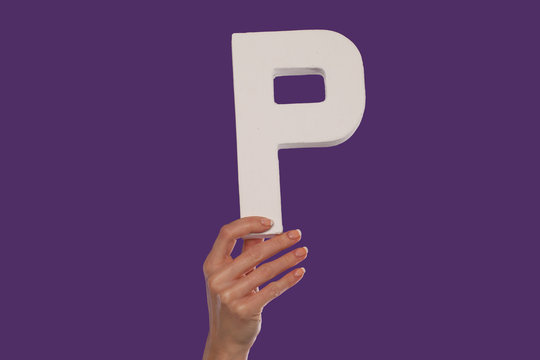 Female hand holding up the letter P from the bottom
