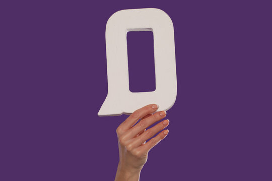 Female hand holding up the letter Q from the bottom