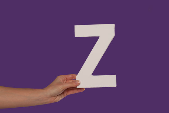 Female hand holding up the letter Z from the left