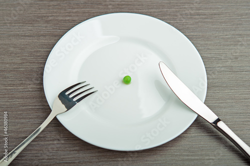Fotografía diet concept. one pea on an empty white plate