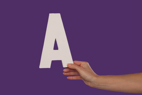 Female hand holding up the letter A from the right
