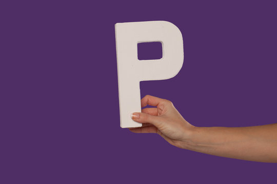 Female hand holding up the letter P from the right