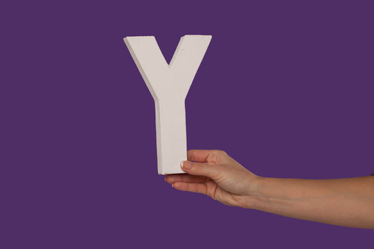 Female hand holding up the letter Y from the right