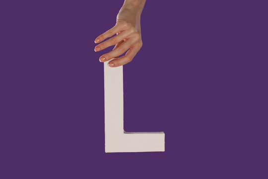 Female hand holding up the letter L from top