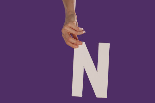 Female hand holding up the letter N from top