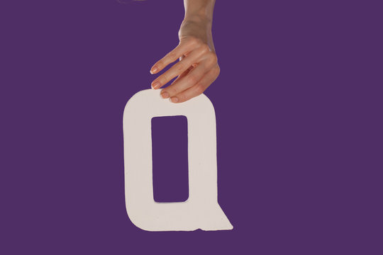 Female hand holding up the letter Q from top