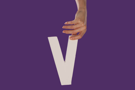 Female hand holding up the letter v from top