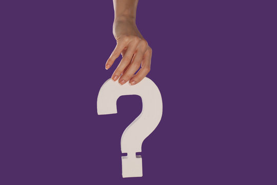 Female hand holding up a question mark from the top