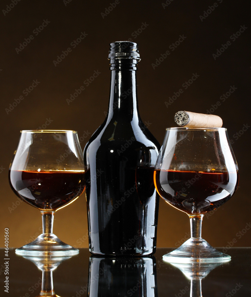 bottle and glasss of brandy and cigar on brown background