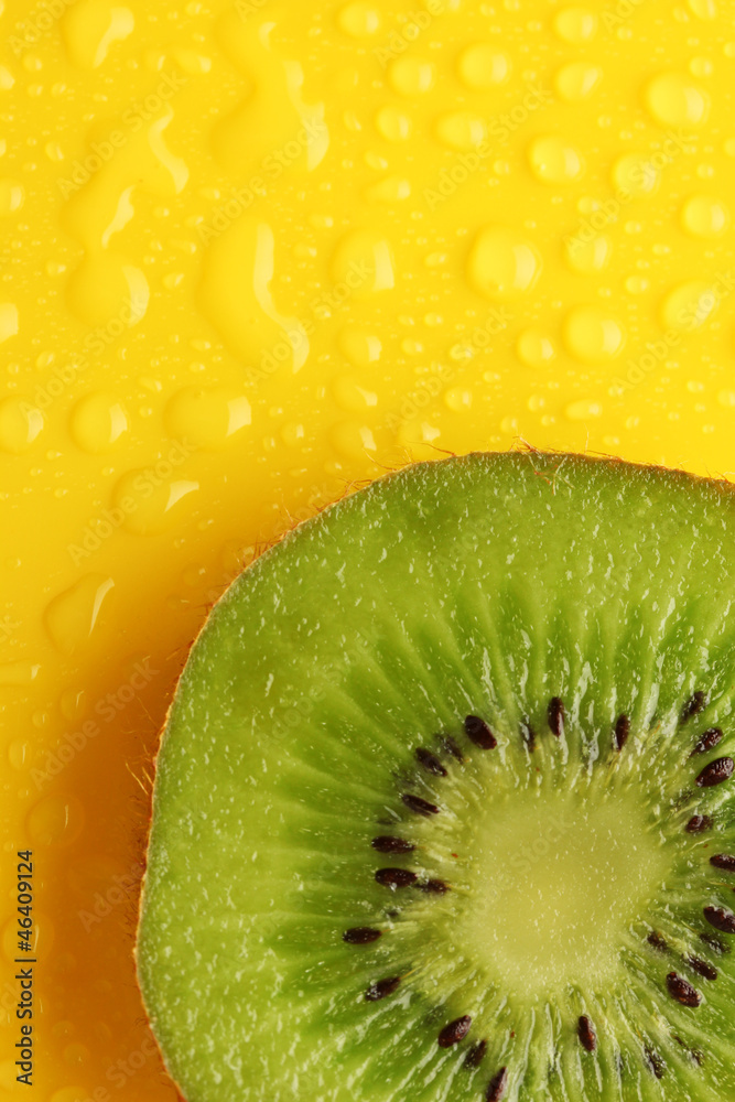 Slice of kiwi with drop on yellow background