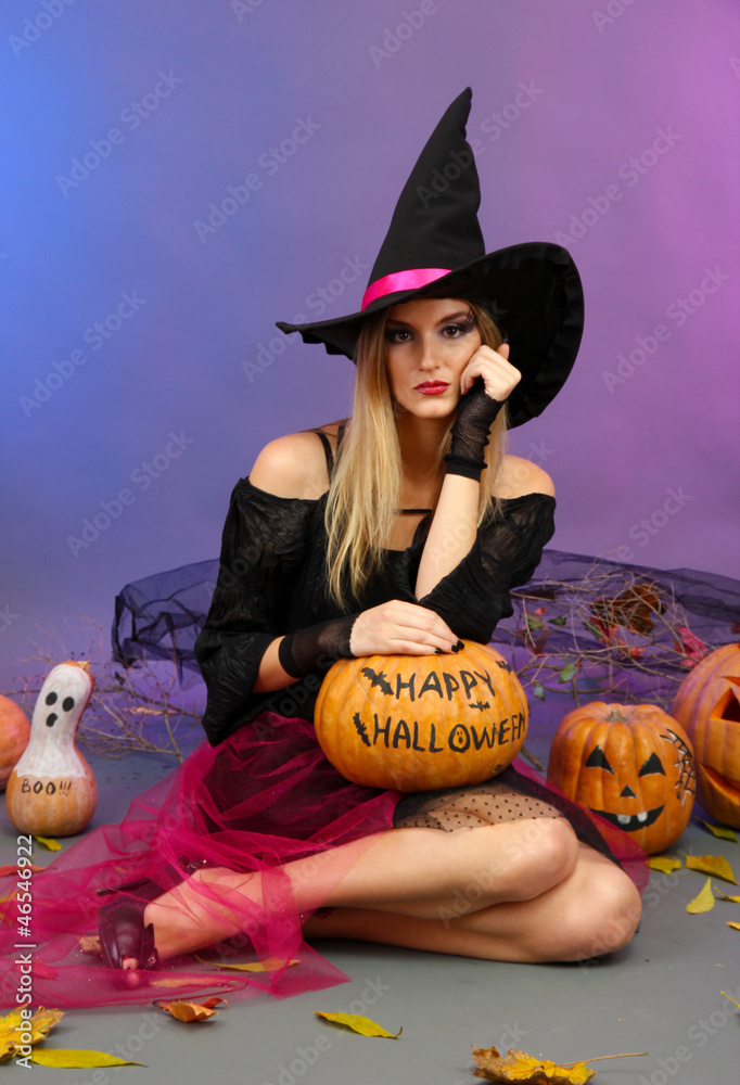 Halloween witch holding pumpkin on color background