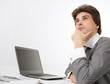 © spaxiax - young business man thinking while working on laptop