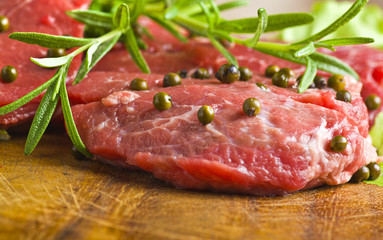 Row Steak whit green pepper and rosemary on plate of wood