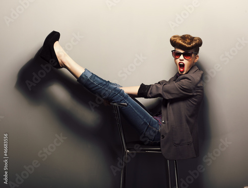 Fototapeta na wymiar Funny girl in sunglasses on chair in studio - vintage