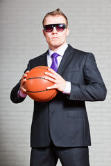 Angry business man with basketball. Wearing dark sunglasses.