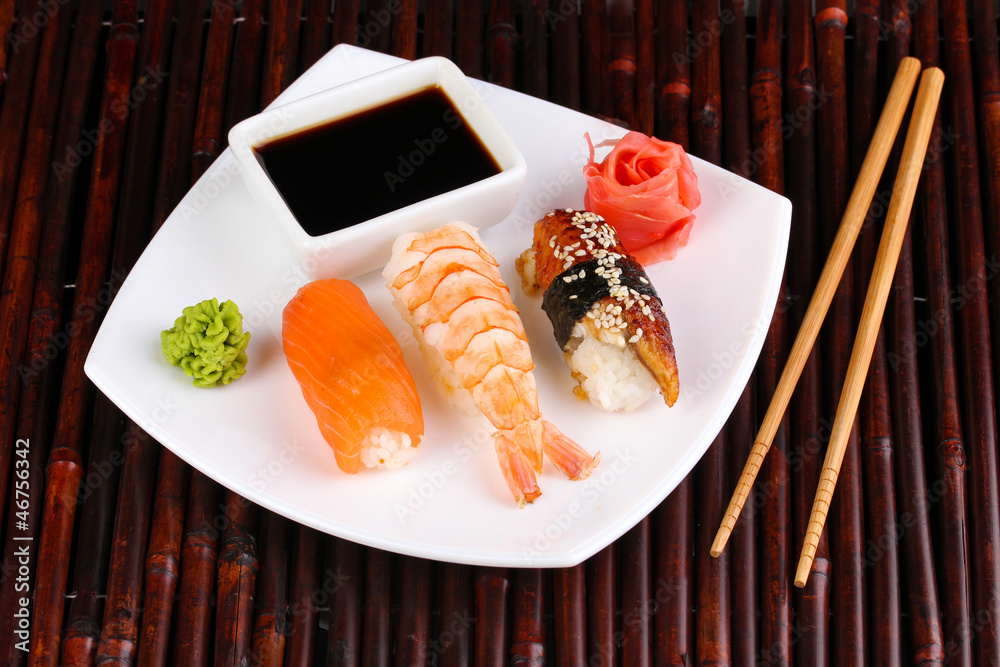 delicious sushi served on plate on bamboo mat