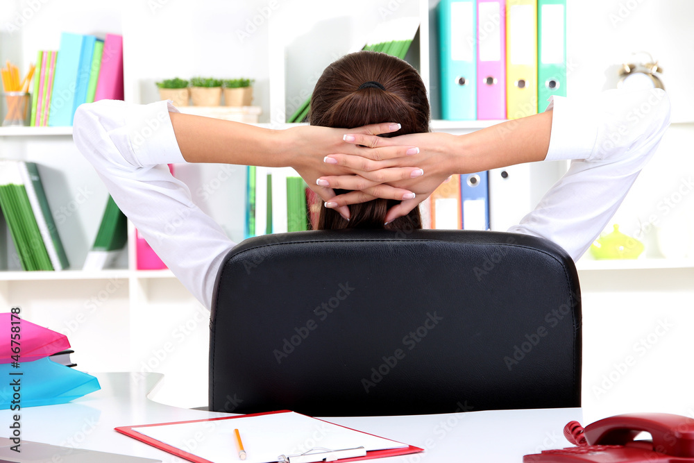 Business woman relaxing in office with hands behind head