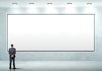 Business person standing near a blank billboard