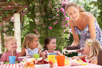 Mother Serving Birthday Cake To Group Of Children Outdoors