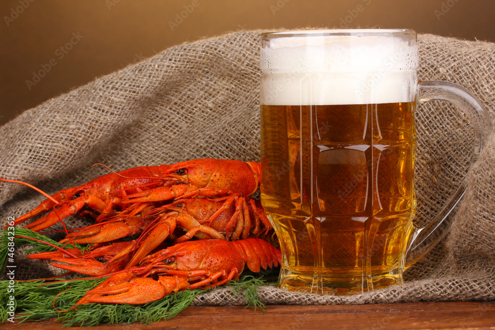 Tasty boiled crayfishes and beer on table on brown background