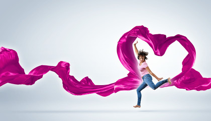Dancing young woman with flying fabric