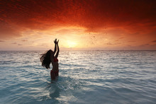 Woman Splashing In Sea On Sunset