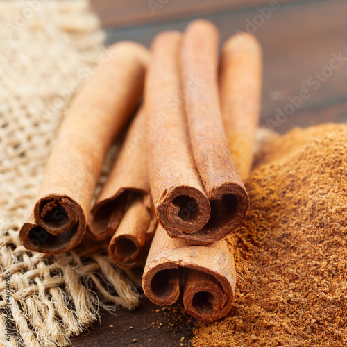 Fotografie, Obraz Cinnamon sticks and powder in wooden scoop