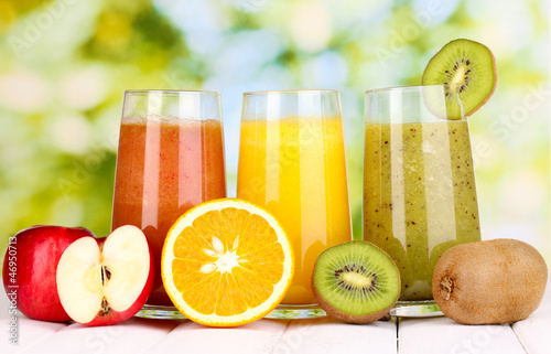 Obraz w ramie fresh fruit juices on wooden table, on green background