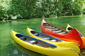 Four empty plastic canoes in turquoise green river