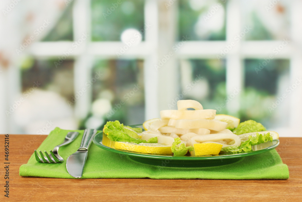 cooked squid rings on lettuce with lemon on the plate close-up