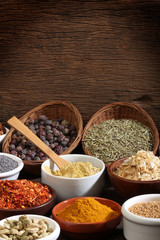 Wall Mural - Different bowls of spices over a wooden background