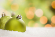 Green Christmas Ornaments On Snow Over An Abstract Background