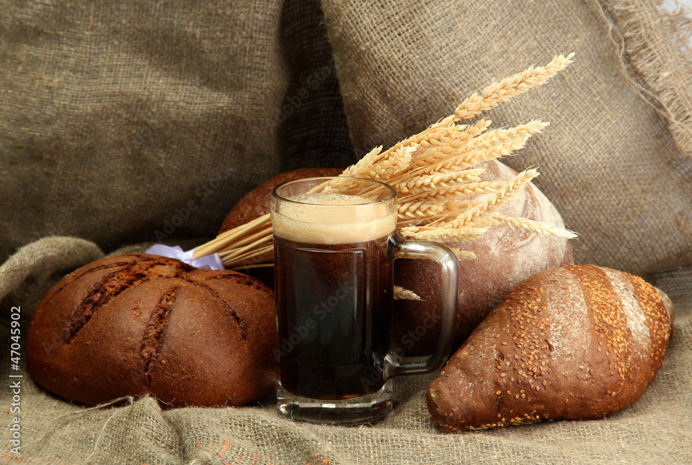 tankard of kvass and rye breads with ears, on burlap background