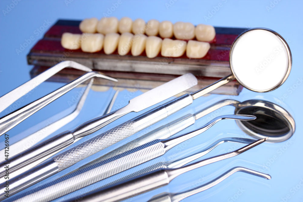 Set of dental tools with denture on blue background