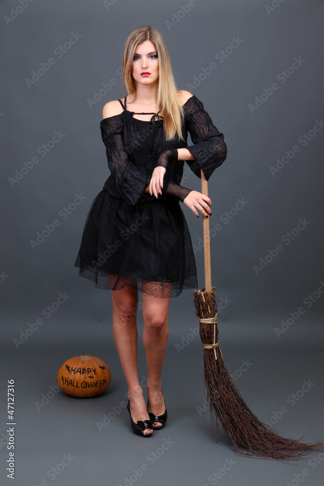 Halloween witch with  broom on gray background
