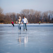 © lightpoet - Couple ice skating outdoors on a pond on a lovely sunny winter d