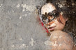 Portrait of beautiful woman over dirty wall with venetian mask