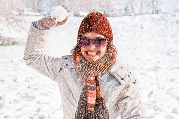 Happy young woman playing snowball fight