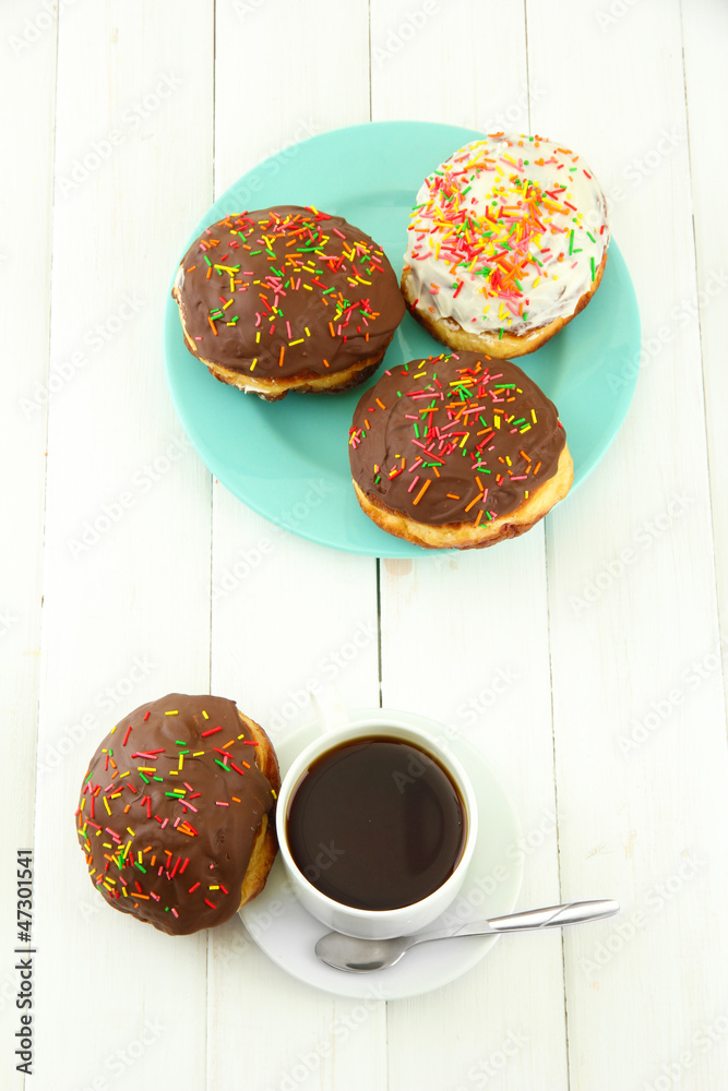 Tasty donuts on color plate on light wooden background