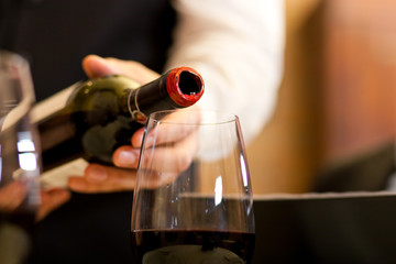 Waiter serving red wine with bottle at the restaurant