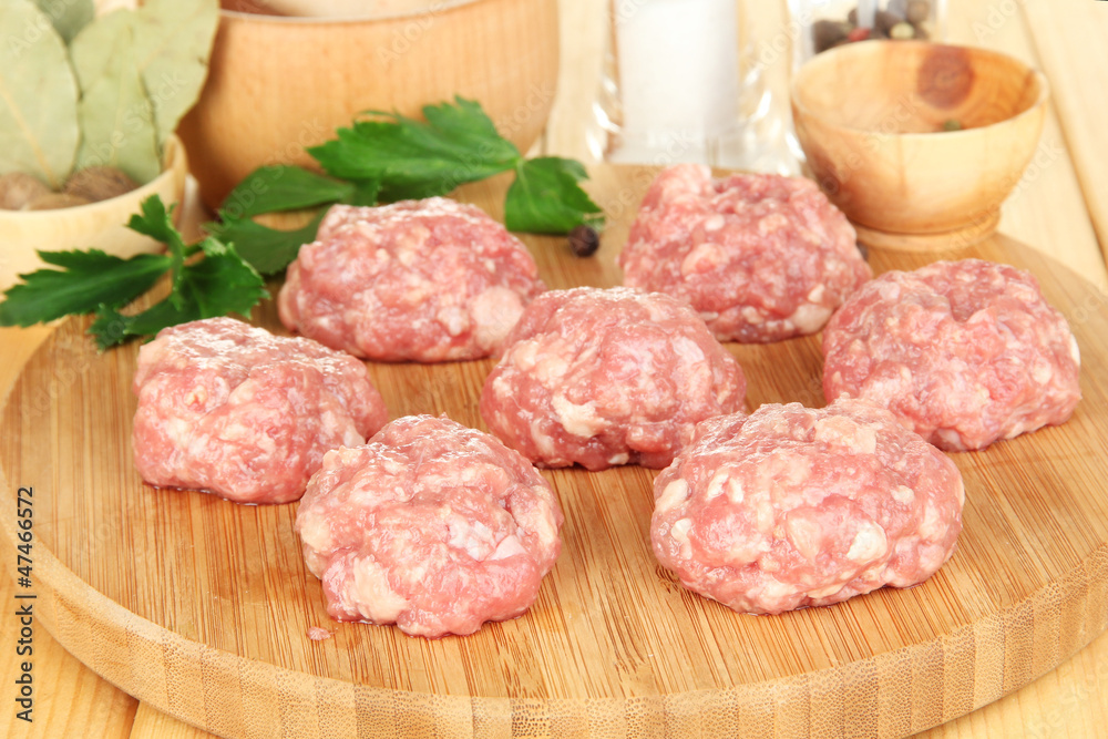 Raw meatballs with spices on wooden table