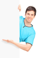 Wall Mural - A smiling handsome male gesturing behind a panel