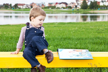 Веселый и милый мальчик в парке читает книгу