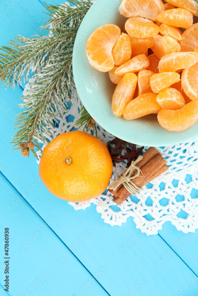 Tasty mandarine's slices on color plate on blue background