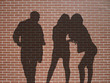 ombres 1 homme 2 femmes sur mur de briques